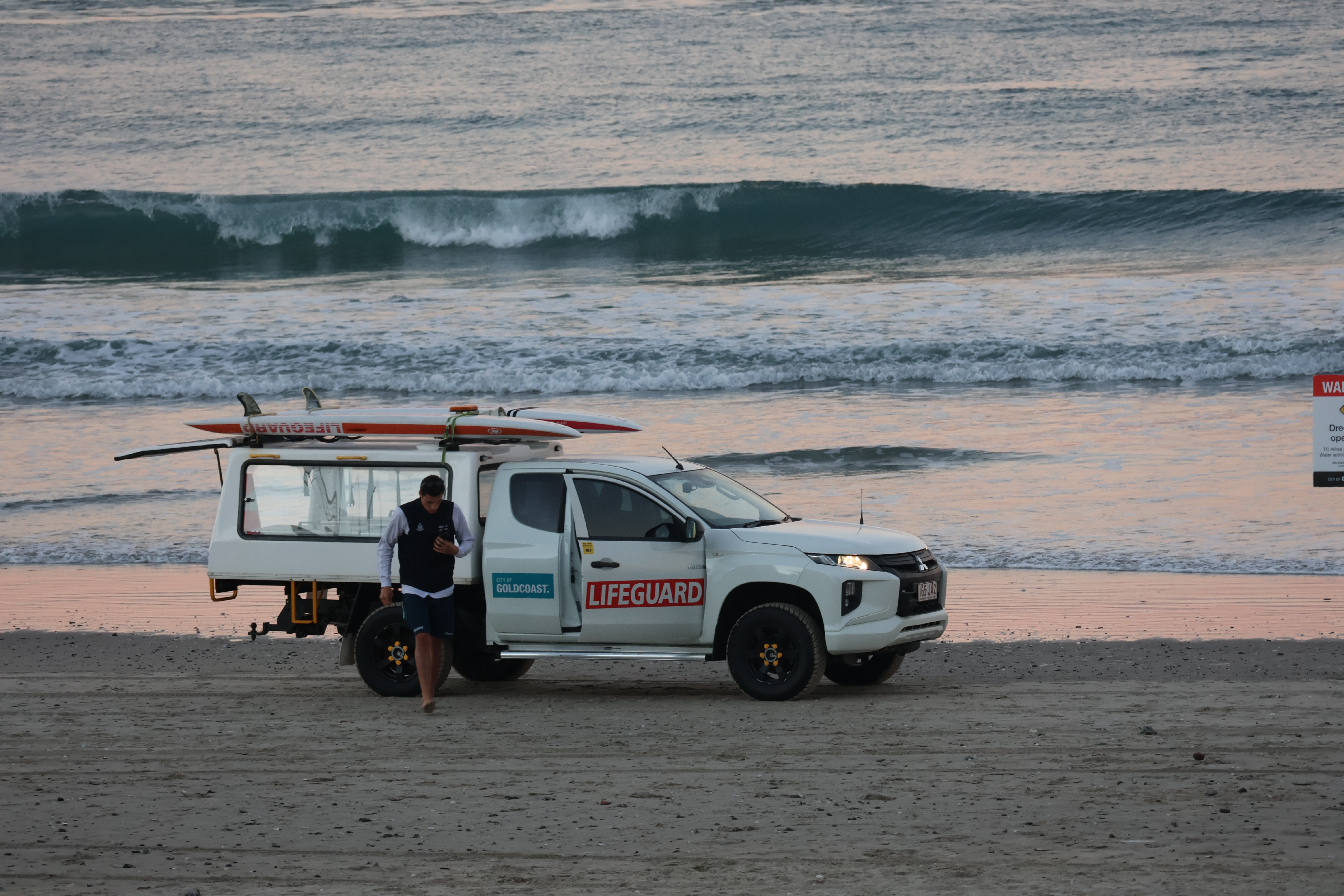 man on beach by a ute
