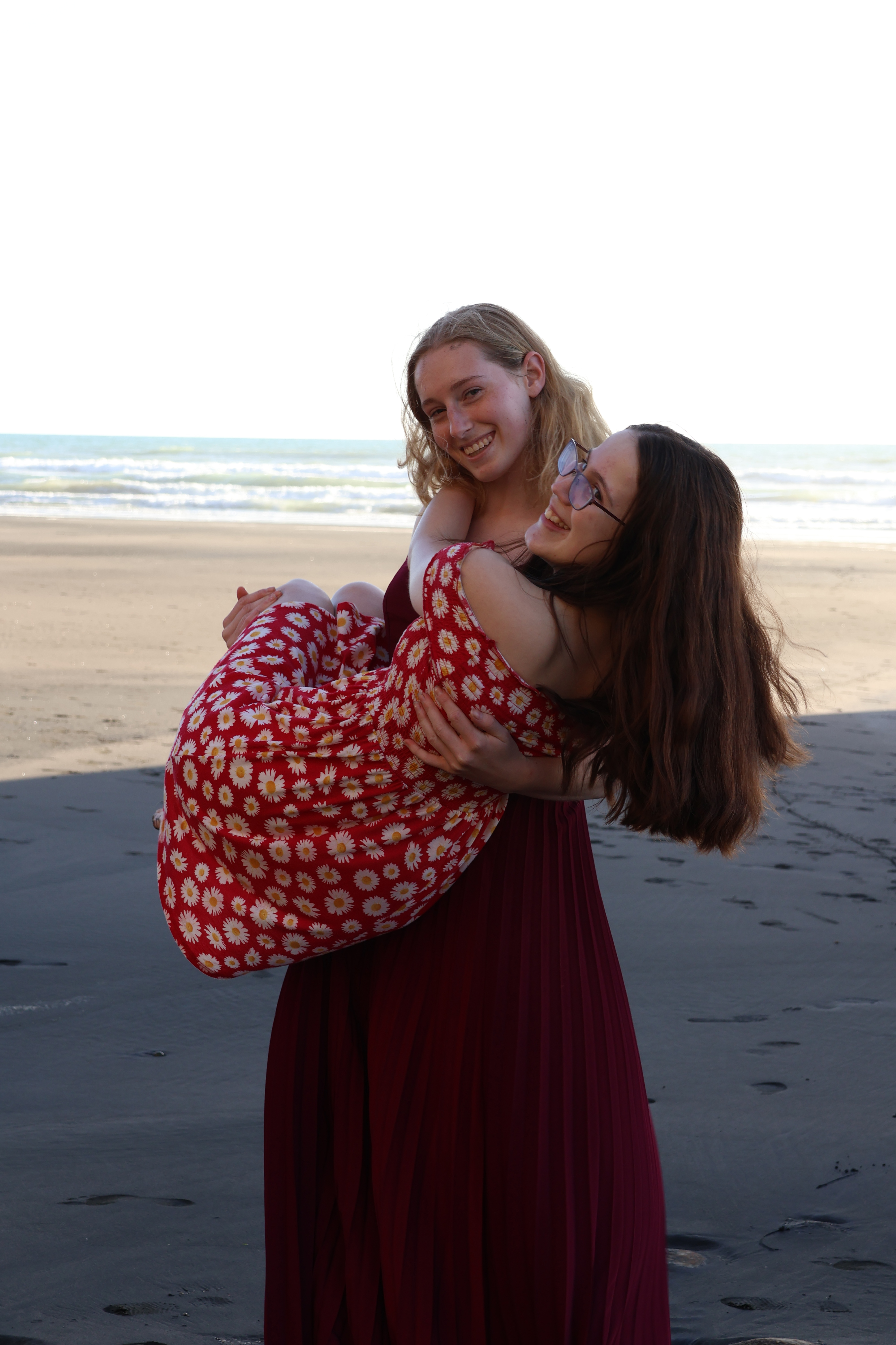 2 girls on beach on holding the other